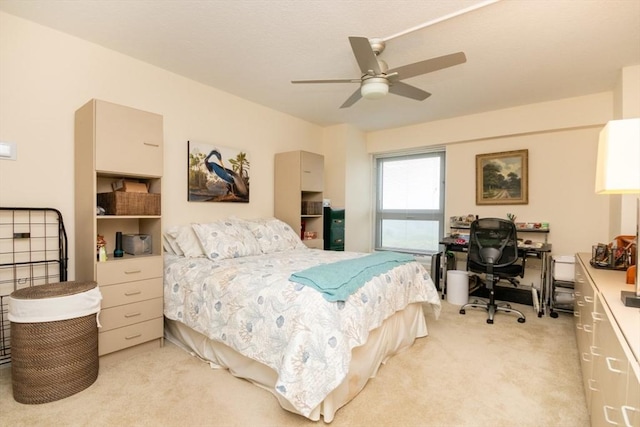 bedroom with light colored carpet, a desk, and a ceiling fan