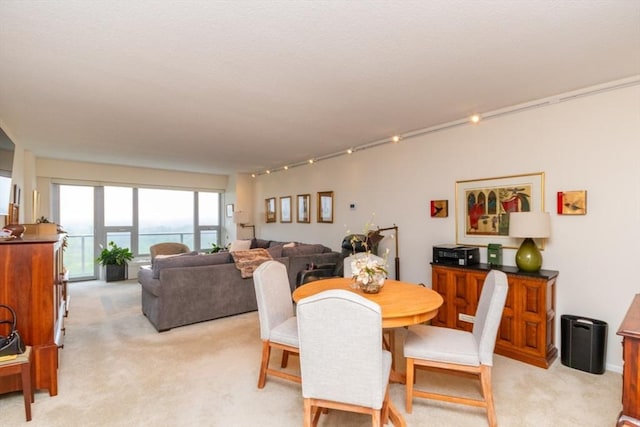 dining space with light colored carpet and track lighting