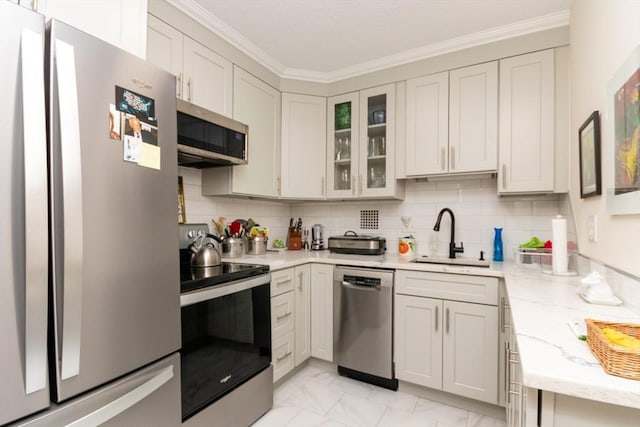 kitchen featuring appliances with stainless steel finishes, a sink, light marble finish floors, glass insert cabinets, and crown molding
