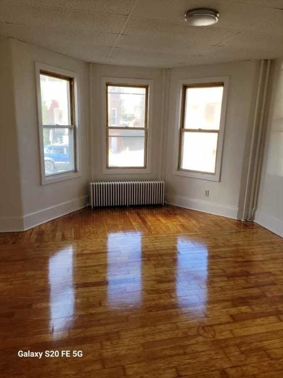 empty room featuring radiator heating unit and wood-type flooring