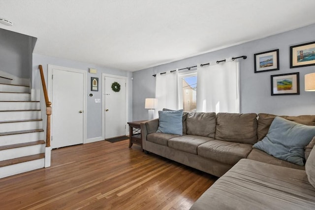 living room with wood finished floors, baseboards, and stairs