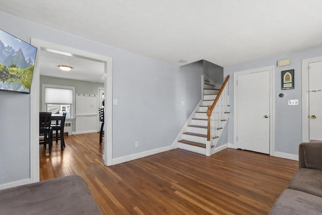 living room featuring stairs, wood finished floors, and baseboards