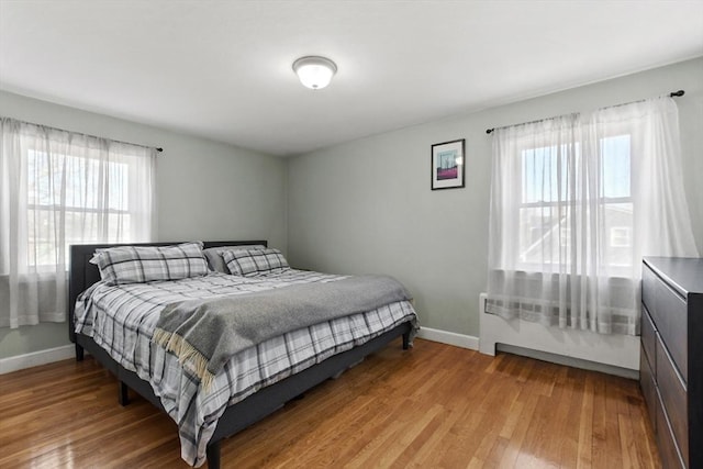 bedroom featuring light wood-style floors, multiple windows, and baseboards