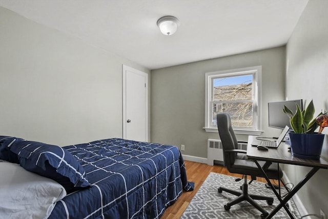 bedroom featuring radiator heating unit, wood finished floors, and baseboards