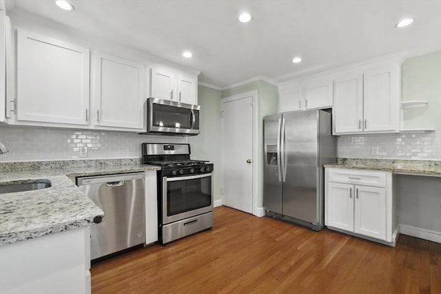 kitchen featuring stainless steel appliances, wood finished floors, a sink, and white cabinets