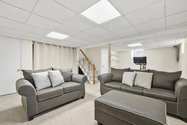 carpeted living area with stairs and a paneled ceiling