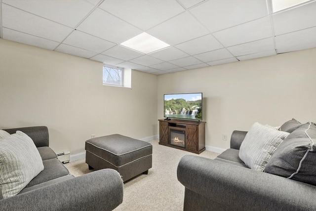 living area with carpet, a paneled ceiling, a baseboard heating unit, a glass covered fireplace, and baseboards