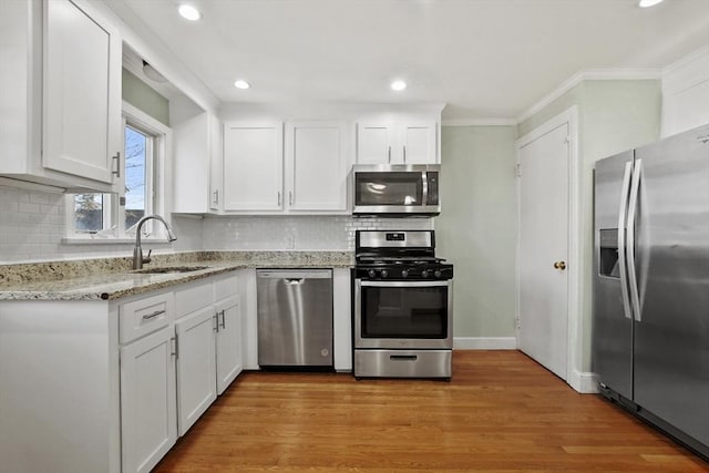 kitchen featuring white cabinets, light wood-style floors, stainless steel appliances, and a sink