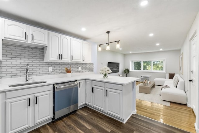 kitchen featuring stainless steel dishwasher, a sink, open floor plan, a peninsula, and white cabinetry