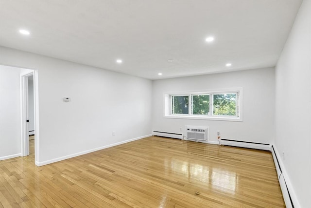 spare room featuring baseboard heating, a baseboard heating unit, light wood-style flooring, recessed lighting, and a wall mounted air conditioner