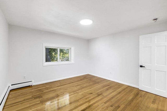 spare room featuring light wood-type flooring, baseboard heating, and baseboards