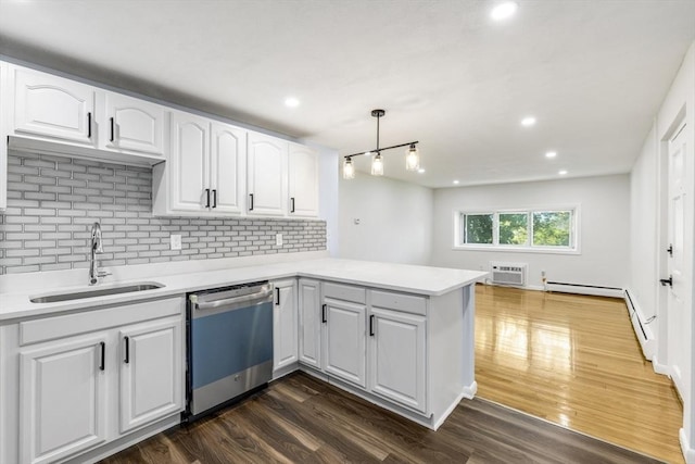 kitchen with dishwasher, a sink, a peninsula, backsplash, and dark wood-type flooring