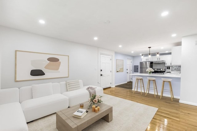 living room featuring light wood finished floors, recessed lighting, and baseboards