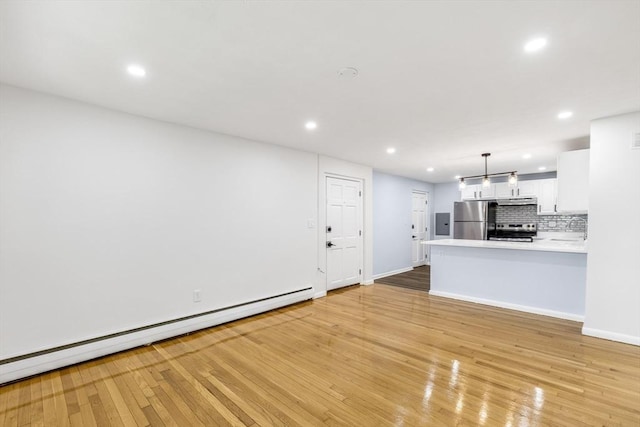 unfurnished living room featuring baseboard heating, recessed lighting, a sink, light wood-style floors, and baseboards
