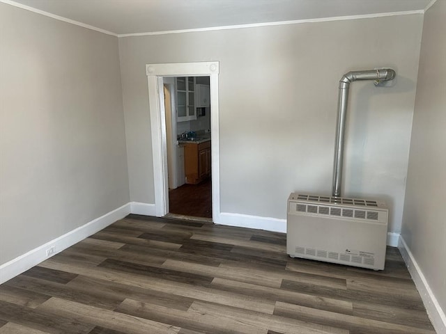 unfurnished living room with heating unit, crown molding, baseboards, and dark wood-style flooring