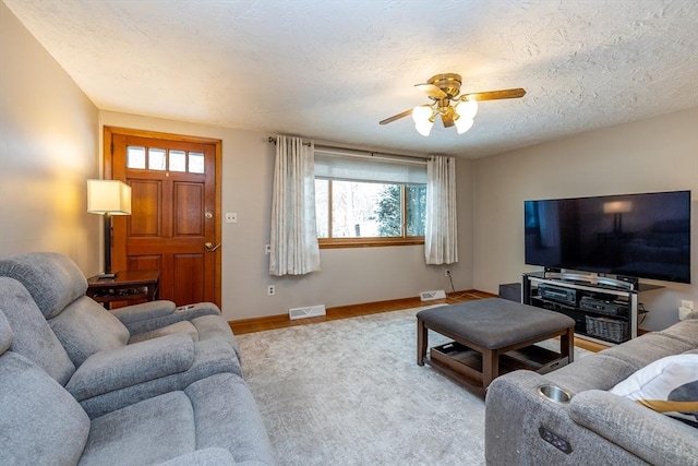 living room with ceiling fan, plenty of natural light, light hardwood / wood-style floors, and a textured ceiling