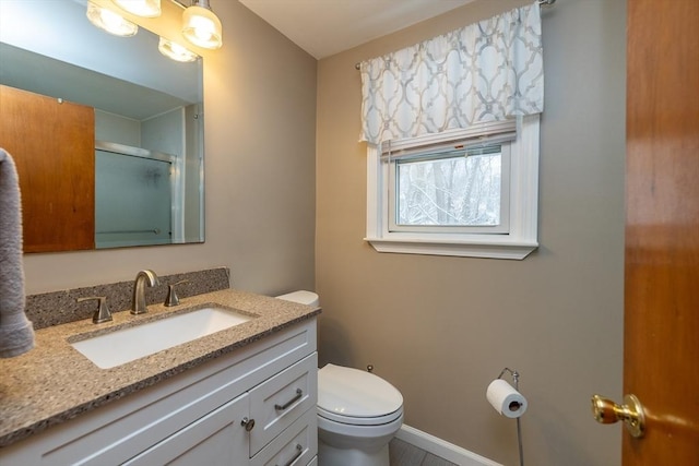 bathroom featuring vanity, a shower with shower door, and toilet