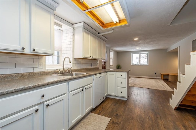 kitchen with dishwasher, sink, kitchen peninsula, and white cabinets