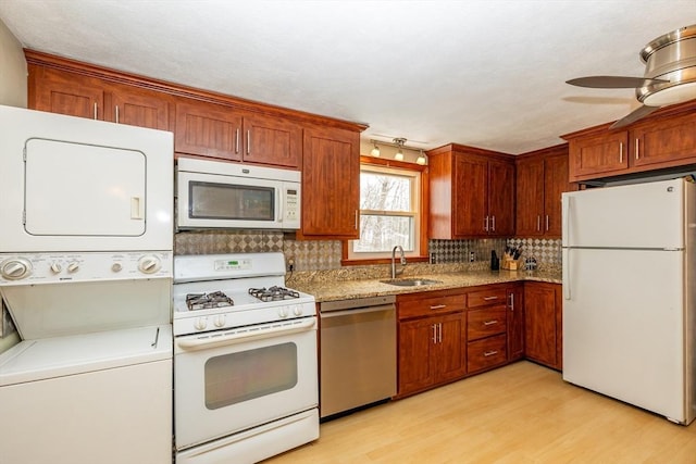 kitchen with stacked washer / dryer, sink, ceiling fan, light hardwood / wood-style floors, and white appliances