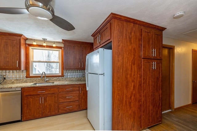 kitchen with tasteful backsplash, stainless steel dishwasher, sink, and white fridge