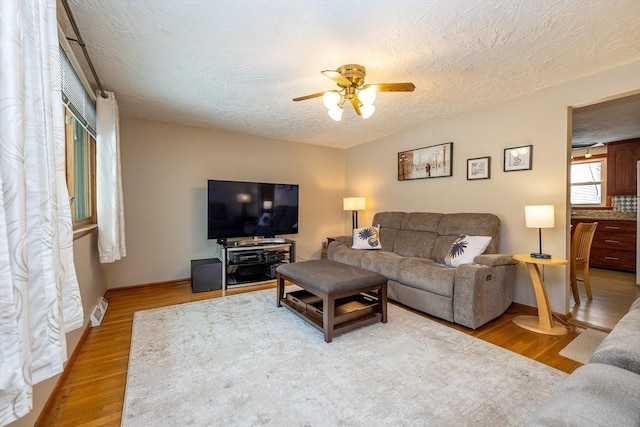 living room featuring ceiling fan, hardwood / wood-style flooring, and a textured ceiling