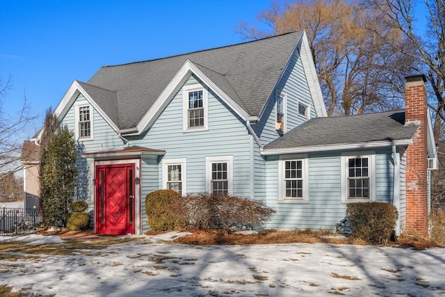 view of front of home with roof with shingles, fence, and a chimney