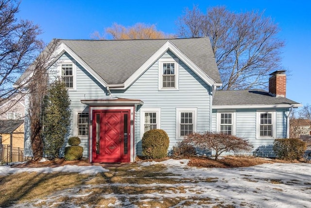 traditional-style home featuring a chimney and roof with shingles