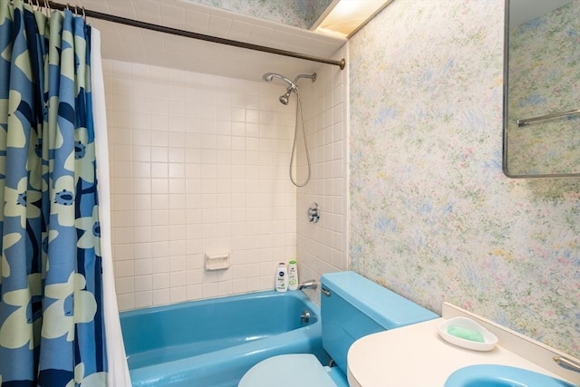 bathroom featuring a sink, shower / bath combo with shower curtain, toilet, and wallpapered walls