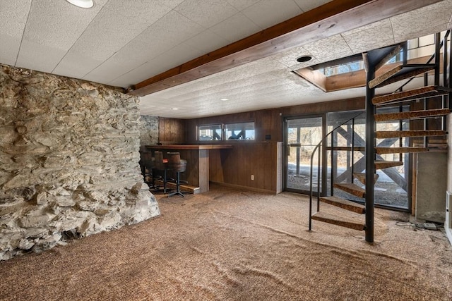 below grade area with stairs, carpet floors, a bar, and wooden walls