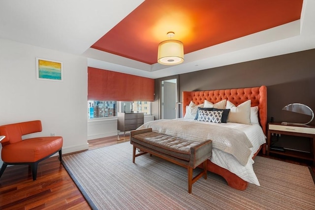 bedroom with dark wood-type flooring and a tray ceiling