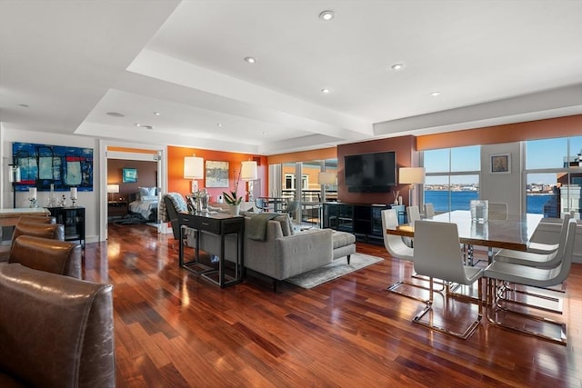 living room featuring a healthy amount of sunlight, hardwood / wood-style floors, and a tray ceiling