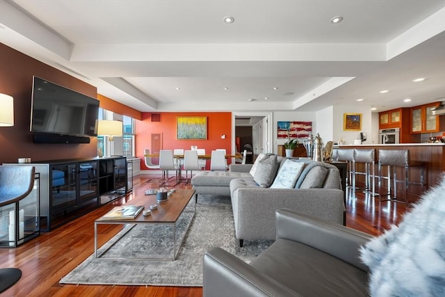 living room with a raised ceiling and hardwood / wood-style flooring