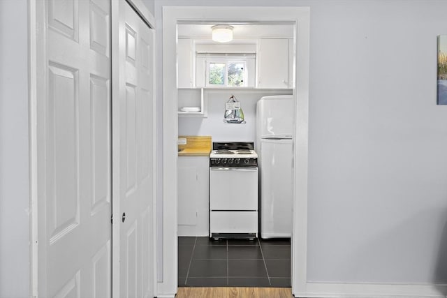 hall featuring dark tile patterned flooring