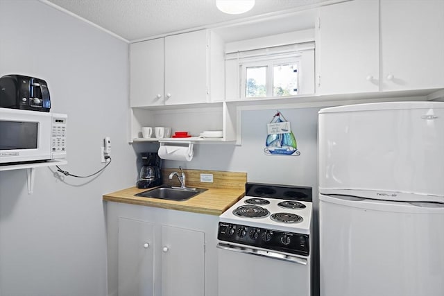 kitchen with white appliances, white cabinets, a textured ceiling, and sink