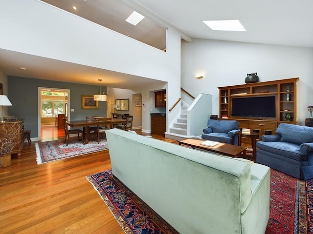 living room featuring a skylight, wood-type flooring, and high vaulted ceiling