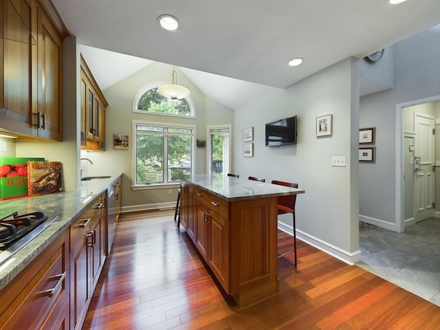 kitchen with lofted ceiling, a breakfast bar area, dark hardwood / wood-style floors, stone counters, and sink