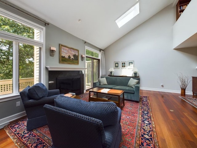 living room featuring high vaulted ceiling, a skylight, and hardwood / wood-style floors