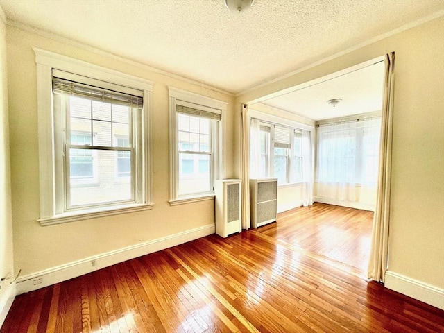 132 Sewall Ave Unit B, Brookline, MA 02446 - spare room featuring radiator heating unit, wood-type flooring, crown molding, healthy amount of natural light, and a textured ceiling