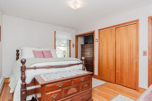 bedroom with a baseboard radiator, light hardwood / wood-style flooring, and a closet