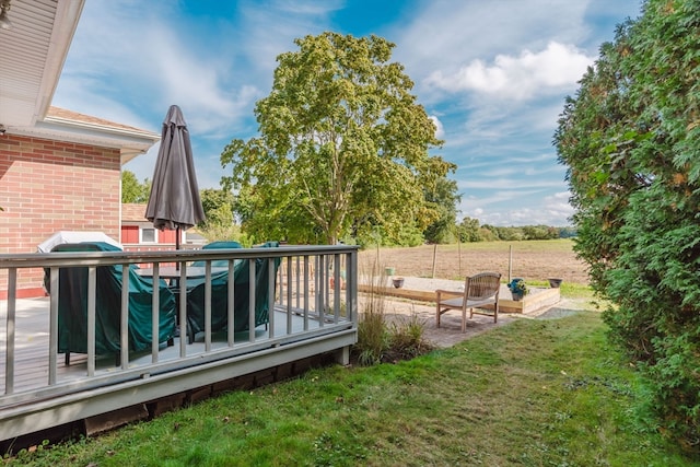 wooden terrace featuring a rural view and a yard