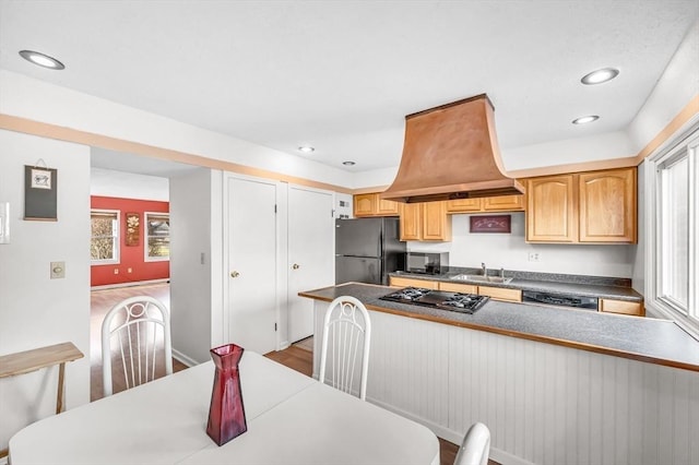 kitchen with sink, black refrigerator, light hardwood / wood-style floors, and gas cooktop