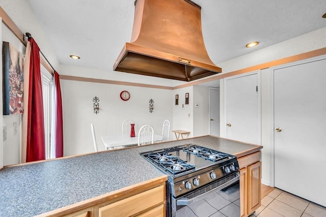 kitchen with light brown cabinets, black gas stove, light tile patterned floors, and exhaust hood