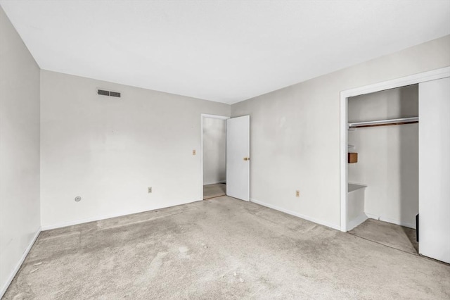 unfurnished bedroom with light carpet and a closet