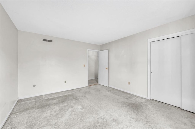 unfurnished bedroom with light carpet and a closet