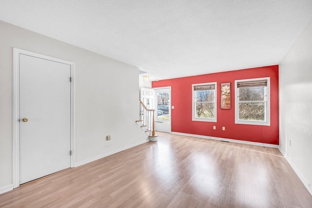 unfurnished room with light hardwood / wood-style floors and a textured ceiling