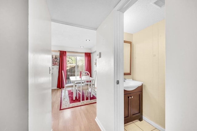 hallway with light wood-type flooring and sink