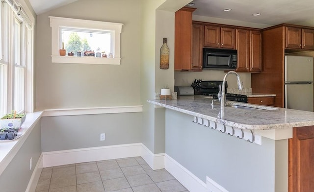 103 Maple Rd, Longmeadow, MA 01106 - kitchen with black microwave, brown cabinets, gas stove, light stone countertops, and light tile patterned floors