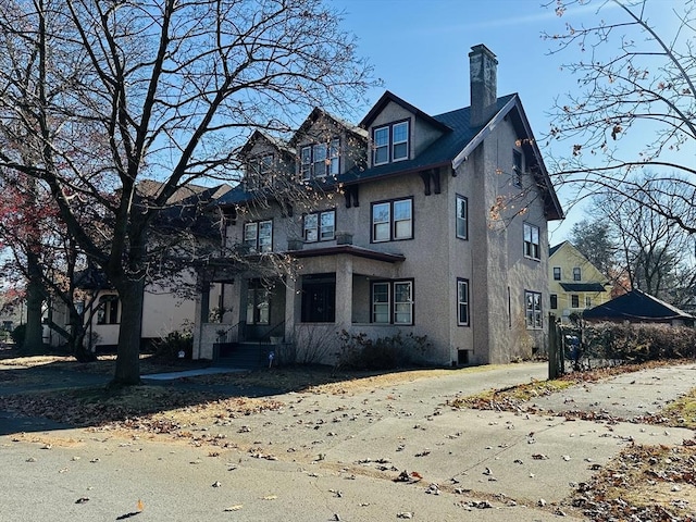 view of front facade with stucco siding and a chimney