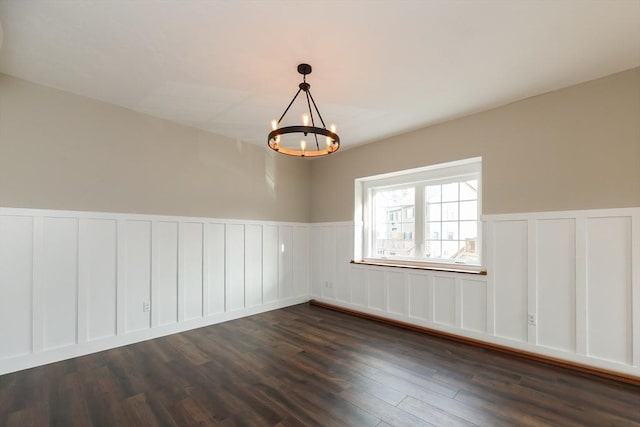 unfurnished room featuring dark wood-type flooring and an inviting chandelier