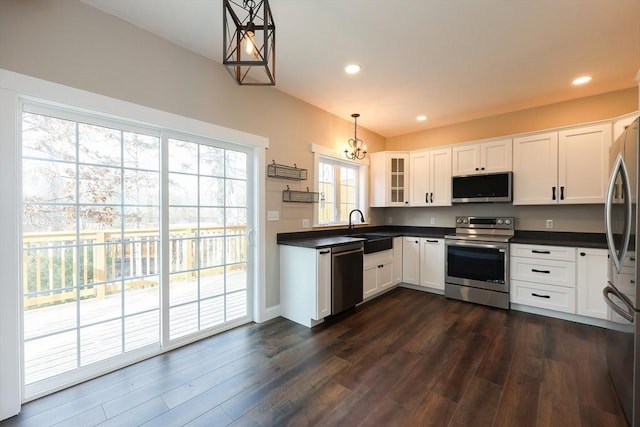 kitchen with appliances with stainless steel finishes, dark hardwood / wood-style floors, decorative light fixtures, white cabinets, and sink